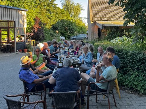 gasten op het buitenterras aan lange tafel